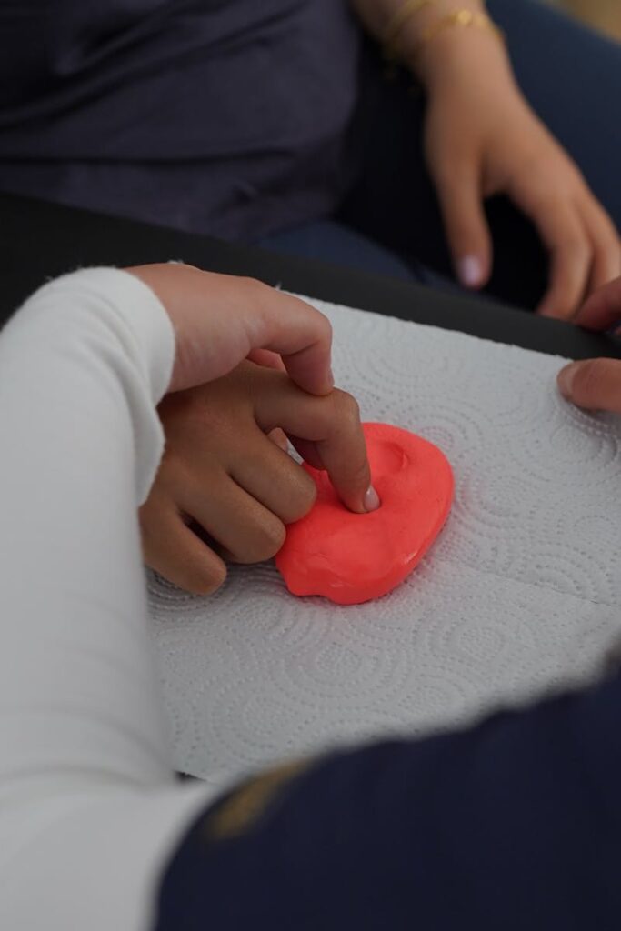 Close-up of hands manipulating putty during therapy session, emphasizing motor skills.