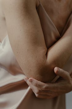 A soft focus close-up of a person's arm touching the elbow in gentle light.